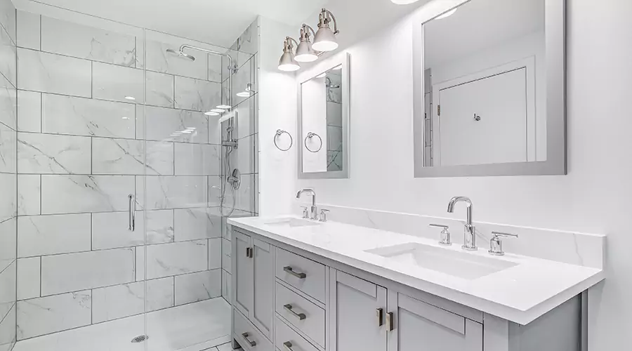 Modern bathroom remodel featuring a dark wood floating vanity, grey tile walk-in shower with sliding glass doors, and chrome fixtures
